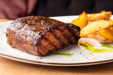 Izgara domuz pirzolası ve kızarmış patatesli ana yemeği beyaz tabakta yakın. Sağlıklı yemek, yakın çekim. Restoranda yemek servisi.