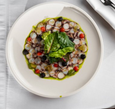 Deniz ürünleri aperatifi. Ahtapot Carpaccio beyaz tabakta. Akdeniz lezzeti işte. Mantar soslu ahtapot carpaccio, acılı jöle ve salatalık reçeli.