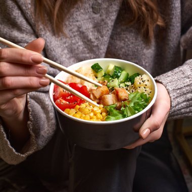 Temiz beslenme konsepti. Avokadolu tavuk kasesi, öğle yemeği arası veren bir kadının elindeki kağıt kutunun içinde. Kapat..