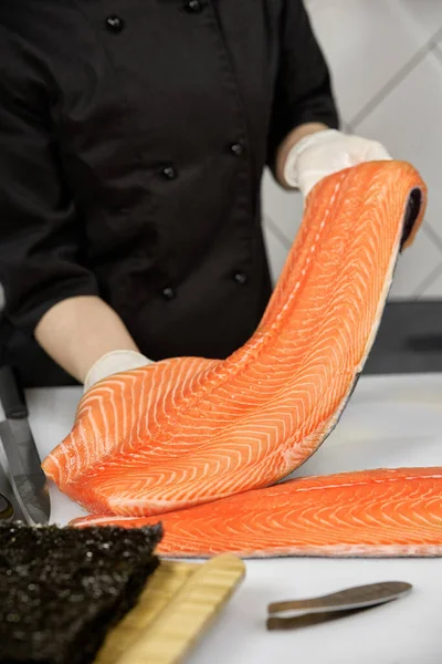 stock image Portrait of cheerful chef standing with salmon fish. Chef cutting fish and making sashimi. The chef cuts the fish and makes sashimi.