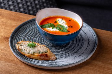 Bir kase kremalı domates çorbası ve taze yeşil fesleğen yapraklı garnitür. Lezzetli. Restoranda servis edilen yemek, menü yemek konsepti..