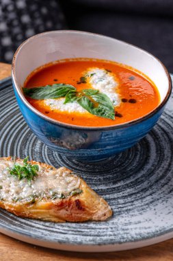 Bir kase kremalı domates çorbası ve taze yeşil fesleğen yapraklı garnitür. Lezzetli. Restoranda servis edilen yemek, menü yemek konsepti..