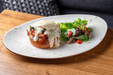 Benedict usulü yumurta, kızarmış İngiliz keki, jambon, haşlanmış yumurta ve lezzetli Hollandez sosu. Lezzetli. Restoranda servis edilen yemek, menü yemek konsepti..