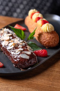 Ahşap arka planda orijinal krem desenli Fransız ekleriydi. Seçici odaklanma. Lezzetli tatlı profiterolleri.