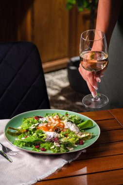 Stracciatella ve hurma salatası ve bir bardak beyaz şarap. Tabakta yemek var. Restoran menüsü konsepti. Uzayı kopyala Düz yatıyordu.