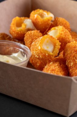 Lezzetli peynirli mozzarella çubukları siyah bir tabakta karanlık bir grupta. Derin peynir çubukları, aperatif, fast food. Çıtır kraker tabağı..