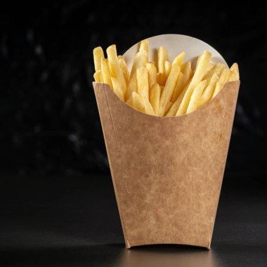 Kağıt sepette büyük porsiyon patates kızartması. Fast Food.Siyah arka planda karton kutuda patates kızartması, menü yemek konsepti..
