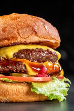 Amerikan peynirli, marullu, domatesli, kırmızı soğanlı, turşulu ve siyah arkaplanlı çift katlı leziz bir çizburger. Lezzetli çizburger. Sandviç, fast food, harika yemekler.