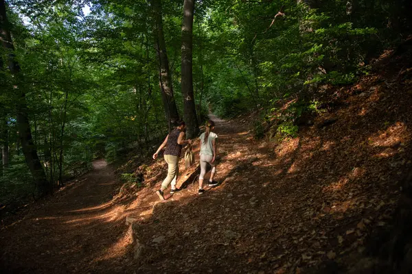 Hiking uphill a mountain. Mom and daughter walk on a path in a steep hillside. Brasov, Romania mountain.