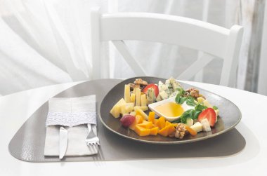 Farklı peynirli peynir tabağı ve beyaz arka planda meyveler. Parti için aperatif. Sağlıklı gıda konsepti. Bir restoranın arka planında