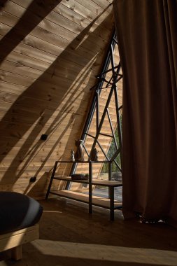 Deri kanepesi ve geniş penceresi olan koyu kahverengi bir iç mekan. Çatı katı tarzı oda.