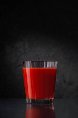 Çiğ organik domates suyu. Yaratıcı minimalist kavram. Asgari yaratıcı gıda konsepti. Karanlık bir taş arka planda.