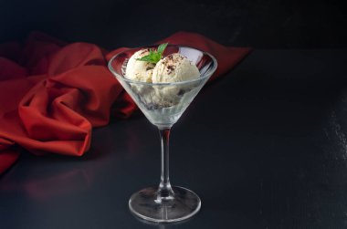 Martini bardağında çikolatalı dondurma ve siyah arka planda nane şekeri. Yaratıcı minimalist kavram. Karanlık bir taş arka planda.