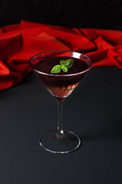 Martini bardağında şarap jölesi, beyaz ve kırmızı şaraptan oluşur, siyah arka planda naneli süsleme. Yaratıcı minimalist kavram. Karanlık bir taş arka planda.