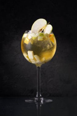 Beyaz şarap ve elmalı sangria, koyu arkaplanda sangria. Yaratıcı minimalist kavram. Karanlık bir taş arka planda.