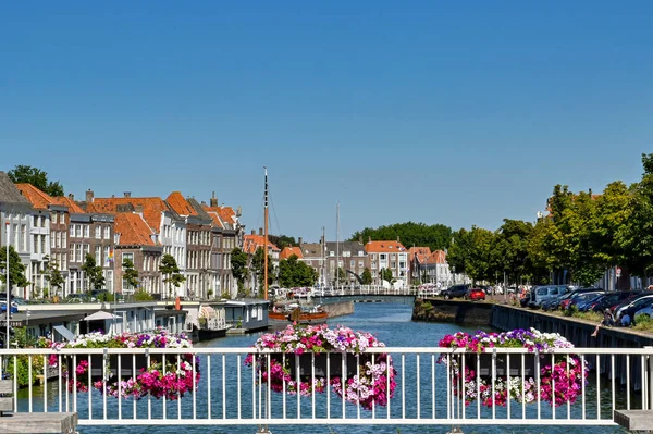 stock image Middleburg, Netherlands - August 2022: Colourful baskets of flowers on the railings of a bridge overlooking the harbour near the city centre