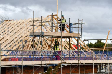 Pontypridd, Galler - Ekim 2022: Bellway Evleri 'nin inşa ettiği yeni bir konut inşaatında çatıda çalışan inşaat işçileri
