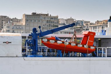 Pire, Atina, Yunanistan - Haziran 2022: Yüksek hızlı kurtarma botu büyük bir feribotun yanındaki vinçte depolandı