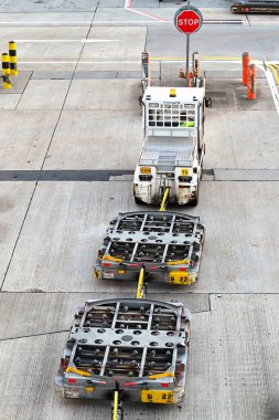 Londra, İngiltere - Ağustos 2022: Havaalanındaki küçük bir traktöre bağlı boş palet römorkları