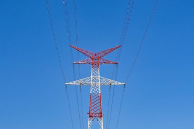 Derin mavi gökyüzüne karşı izole edilmiş elektrik şebekesindeki uzun pilon. Uçağı görebilmek için kırmızı ve beyaza boyanmıştır. Kimse yok..
