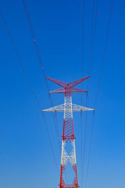 Derin mavi gökyüzüne karşı izole edilmiş elektrik şebekesindeki uzun pilon. Uçağı görebilmek için kırmızı ve beyaza boyanmıştır. Kimse yok..