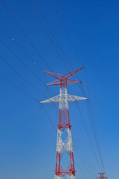 在深蓝色的天空下 电网上的高塔与外界隔绝 它被涂成红色和白色 以便于飞机看到 没有人 — 图库照片
