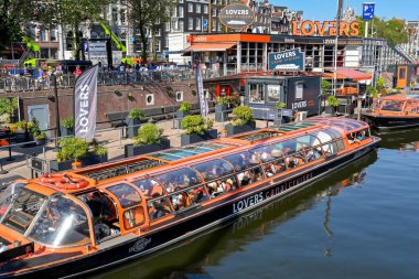Amsterdam, Hollanda - Ağustos 2022: Kanal teknesindeki insanlar şehri gezmek için rıhtımdan ayrılmayı bekliyorlar