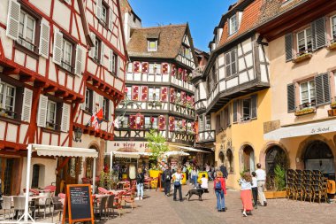 Colmar, Fransa - Nisan 2022: Colmar 'ın merkezindeki eski dekore edilmiş binaların dar sokaklarından birinde yaşayan insanlar