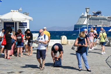 Mykonos, Yunanistan - Haziran 2022: Bir yolcu gemisinden indikten sonra limanın rıhtımında bir harita okuyan ziyaretçi