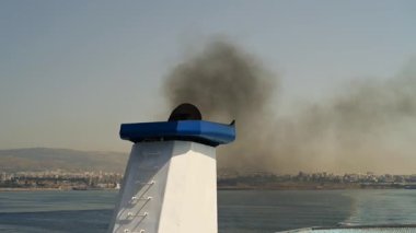 Denizdeki bir geminin bacasından yükselen siyah dumanın yakın görüntüsü