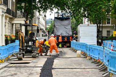 Londra, İngiltere, İngiltere - Haziran 2022: Londra şehir merkezindeki bir sokak üzerindeki yol çalışmaları sonrasında işçiler hendek dolduruyor