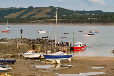 Newquay, Ceredigion, Wales - Ağustos 2022: Liman duvarının sonundaki insanlar liman gezisi için küçük bir tekneye binmeyi bekliyorlar