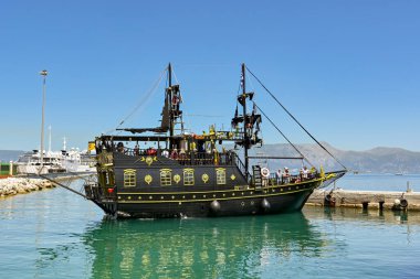 Corfu, Greece - June 2022: Boat in the shape of a pirate ship with tourists on board in the town's harbour.