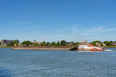Dordrecht, Netherlands - August 2022: Powerful tug pushing heavy industrial barges on the River Maas.