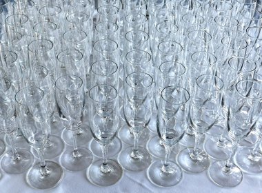 Rows of empty champagne flute glasses on a table at an event waiting to be filled. No people.