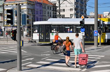 Antwerp, Belgium - August 2022: People with a shopping trolley crossing the road on a pedestrian crossing in the city centre