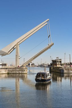 Antwerp, Belgium - August 2022: Road bridge being raaised to allow a small motorboat to leave one of the city's marina