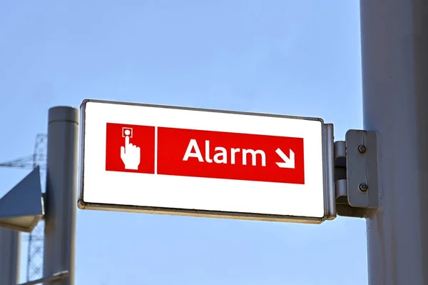 Sign showing the location of an emergency alarm button on a railway station platform
