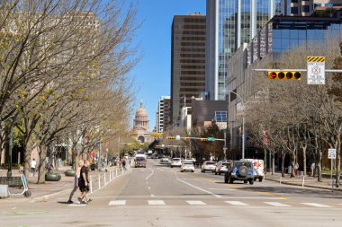 Austin, Texas, USA - February 2023: People crosssing one of the main streets in the city centre. In the background is the State Capitol building..