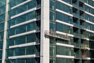 Austin, Teksas, ABD - Şubat 2023: Şehir merkezindeki bir ofis binasının dışında asılı duran bir beşikteki pencere temizleyicileri