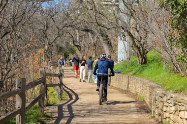Austin, Teksas, ABD - Şubat 2023: Şehir merkezine yakın nehir kenarındaki yolda yürüyen ve bisiklete binen insanlar
