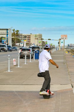 Galveston, Teksas, ABD - Şubat 2023: Kentin gezinti alanında tekerlekli kaykaya binen kişi,