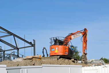 Kilise Köyü, Pontypridd, Galler - Mayıs 2023: Güney Galler 'de yeni bir ilkokul inşaatı için inşaat alanındaki bir toprak yığınının üzerindeki mini kazıcı