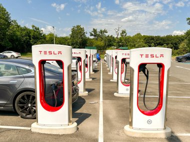 Leigh Delamere, Chippenham, Wiltshire, İngiltere - 25 Haziran 2023: Tesla arabası Swindon yakınlarındaki M4 otoyol benzin istasyonundaki Tesla elektrikli araç şarj istasyonlarından birinden şarj ediliyor.