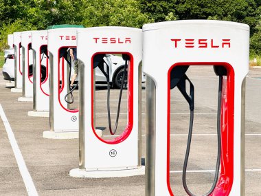 Leigh Delamere, Chippenham, Wiltshire, UK - 25 June 2023: Row of Tesla electric vehicle charging stations at the M4 motorway service station near Swindon. clipart