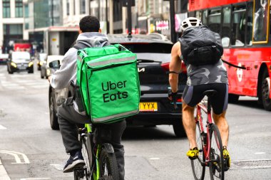 Londra, İngiltere, İngiltere - 28 Haziran 2023: Uber Eats şirketi için izole edilmiş bir teslimat konteynırı taşıyan bisikletçi Londra 'nın merkezinde bir sokakta bir yarışçıyla birlikte bisiklet sürüyor.