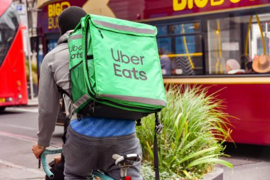 Londra, İngiltere, İngiltere - 28 Haziran 2023: Uber Eats şirketi için izole edilmiş bir teslimat konteynırı taşıyan bisikletçi Londra şehir merkezindeki bir sokakta bisiklet sürüyor.