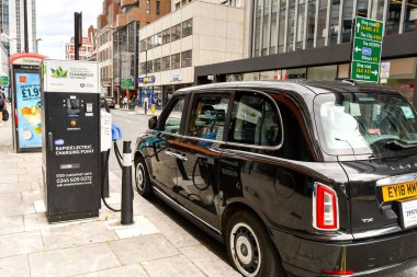 Londra, İngiltere, İngiltere - 27 Haziran 2023: Elektrik taksi Londra şehir merkezindeki bir caddede hızlı şarj noktasına takıldı