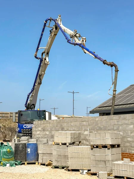 Porthcawl, Galler - 8 Haziran 2023: Porthcawl şehir merkezi yakınlarındaki bir inşaat sahasına hidrolik kolu ve borusu olan beton pompalama makinesi.
