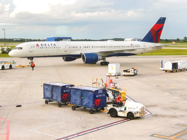 美国佛罗里达州奥兰多 2023年6月24日 德尔塔航空公司波音757客机从奥兰多机场起飞 前景是一辆小型拖拉机拖着行李箱 — 图库照片